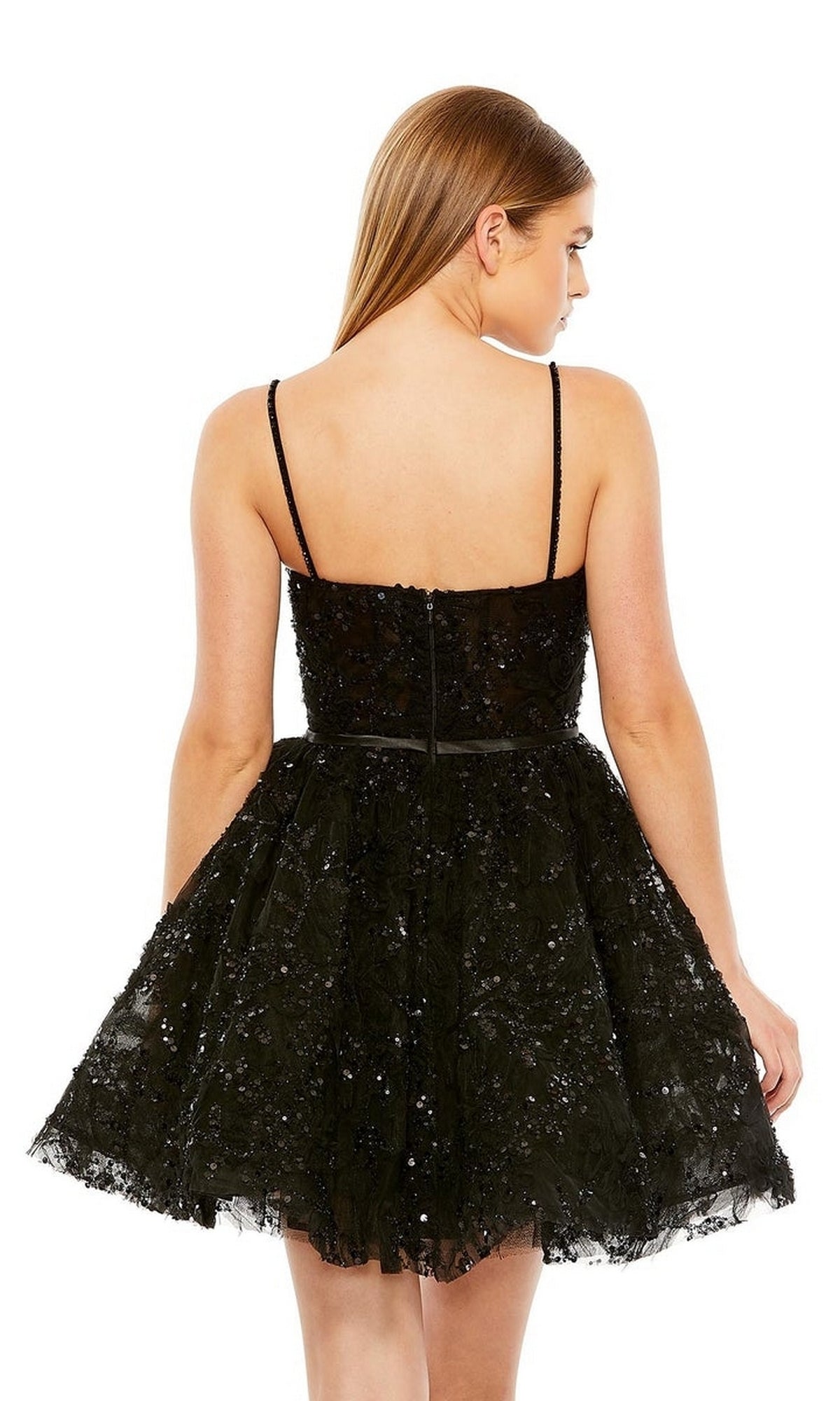 A woman with straight brown hair models the Mac Duggal 20641 short black beaded hoco dress, featuring thin straps and a sweetheart neckline, shown from the back against a plain white background.